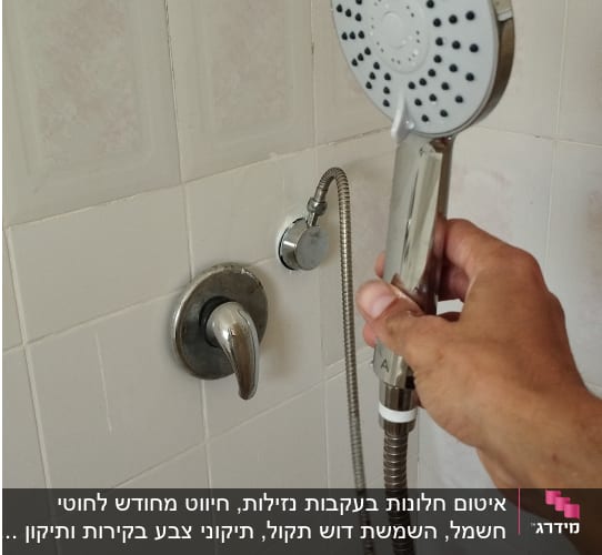 יד מחזיקה ראש מקלחת בחדר אמבטיה